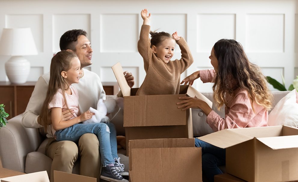 Happy parents and children playing on moving day unpacking boxes